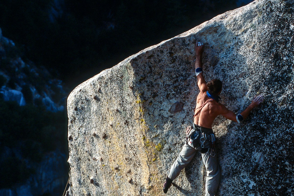 A climber ascending a sunlit rock face in Yosemite