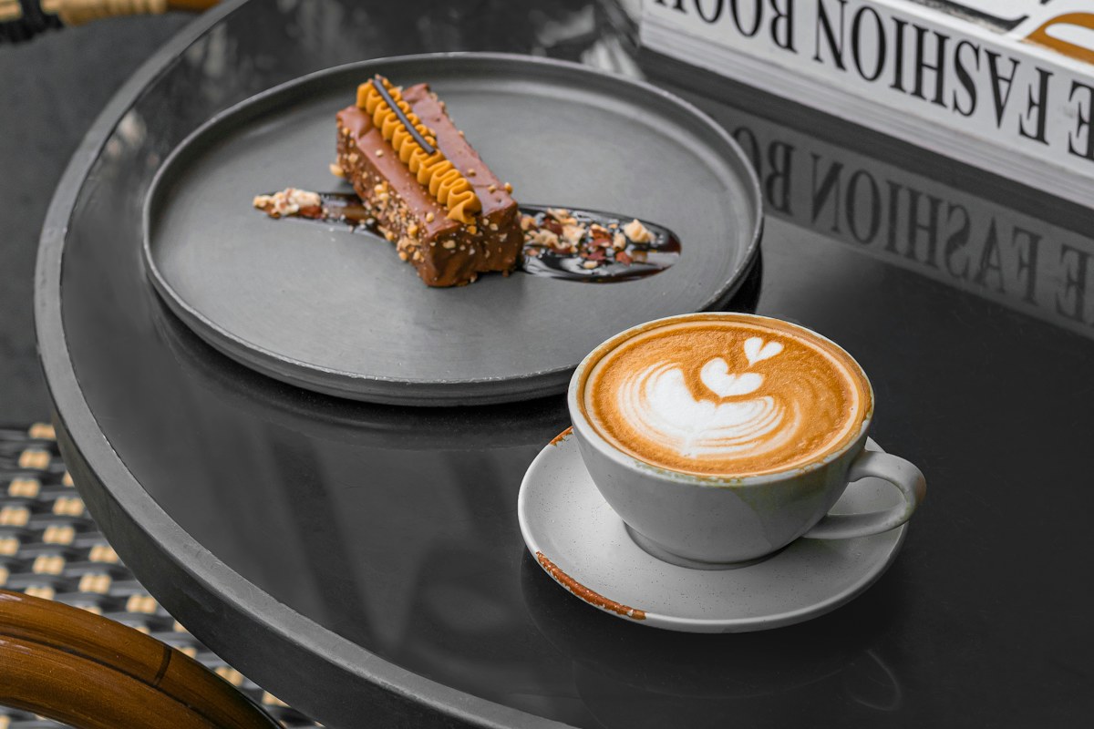 A cup of coffee beside a pastry on a cafe table