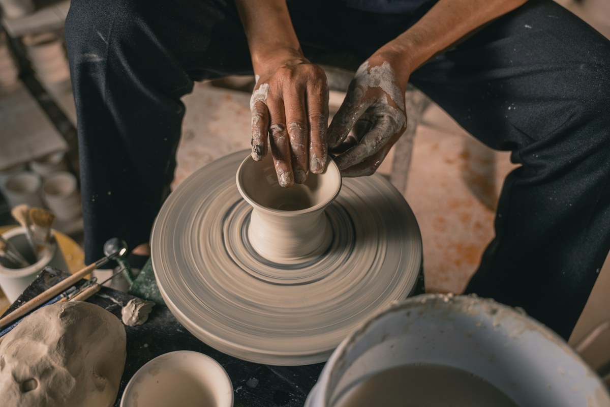Hands shaping clay at a pottery wheel