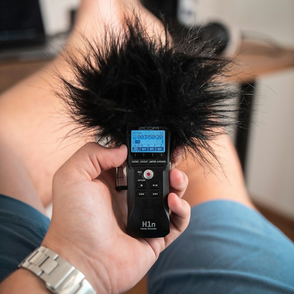 Hand holding a portable audio recorder with windscreen
