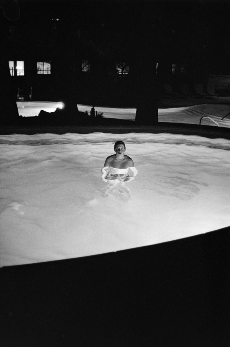 Person in a lit swimming pool at night