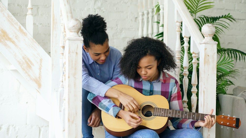 Two people learning guitar together