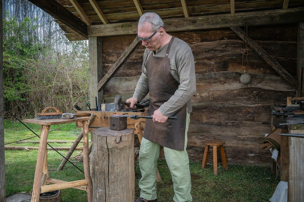 Blacksmith working at an anvil in a rustic workshop