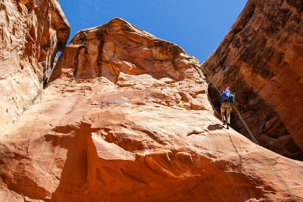 Rappelling down a red sandstone canyon wall