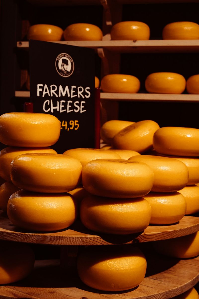 Cheese wheels stacked on wooden shelves.
