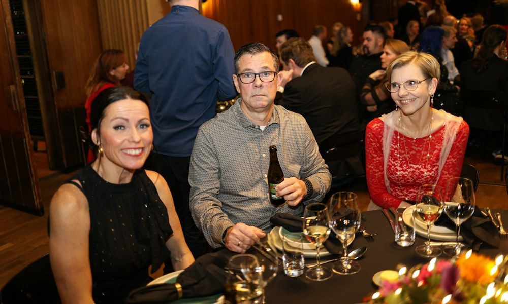 Three people talking at a formal dinner table