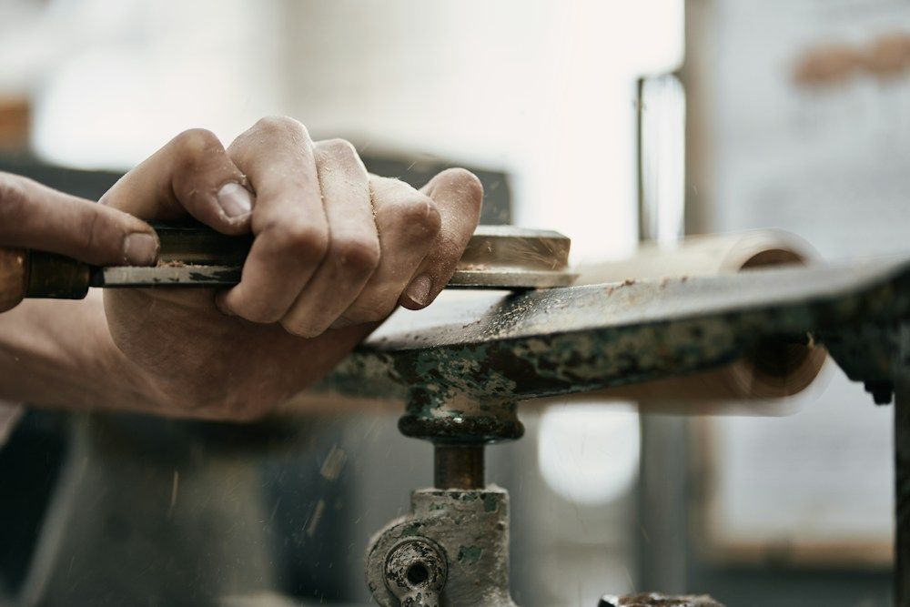 Hands shaping wood with a lathe and chisel