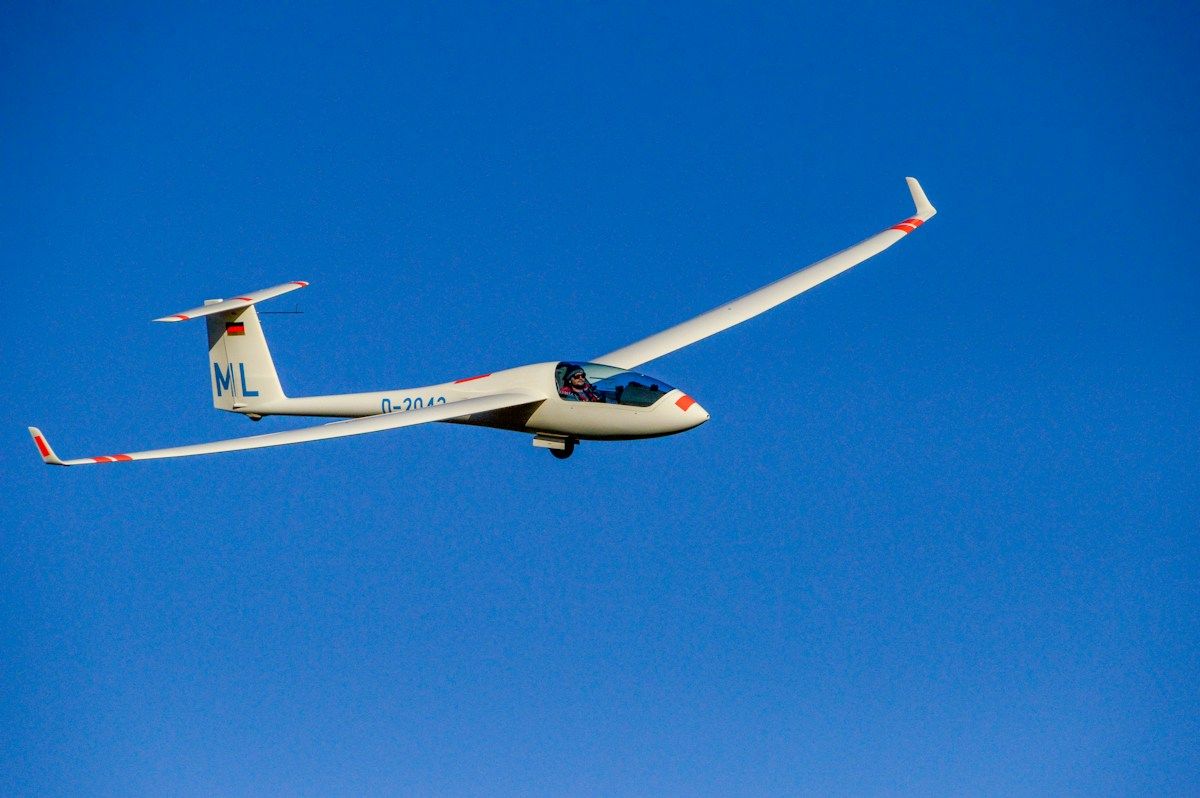 White glider soaring over countryside