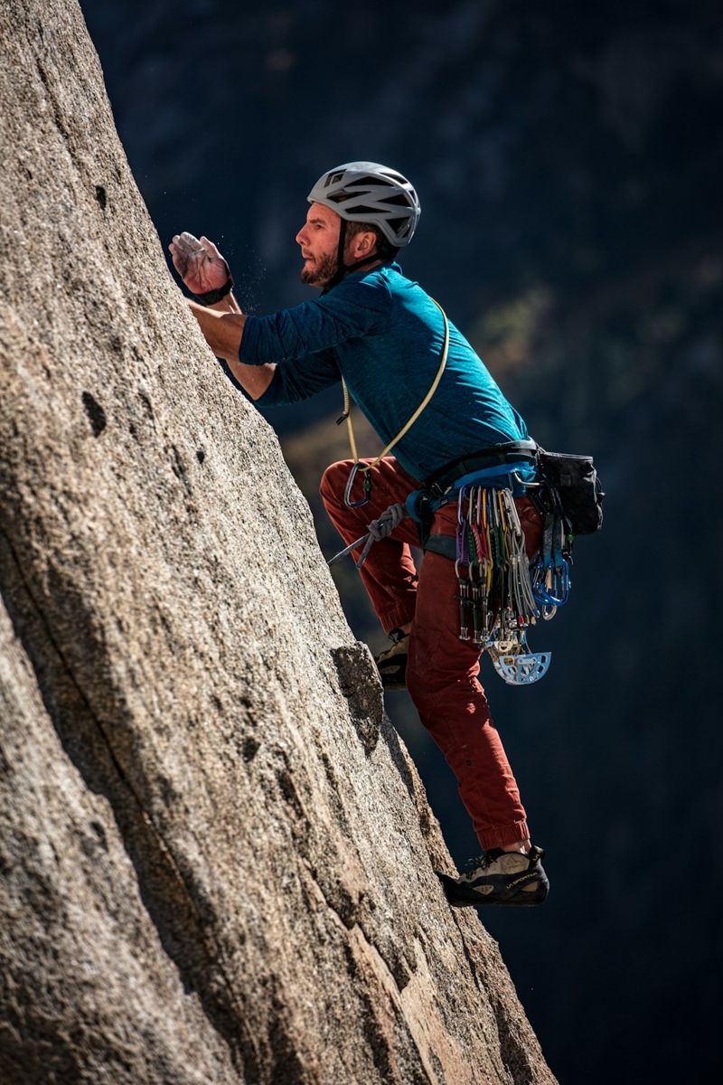 Helmeted climber on a rock face with safety rope