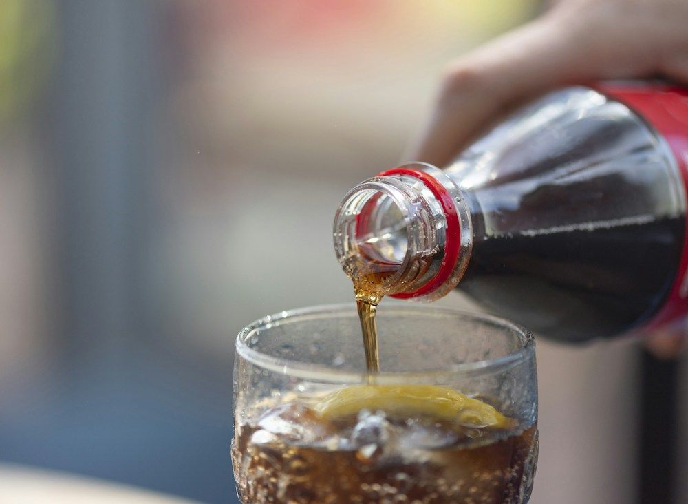 Soda poured into glass over ice