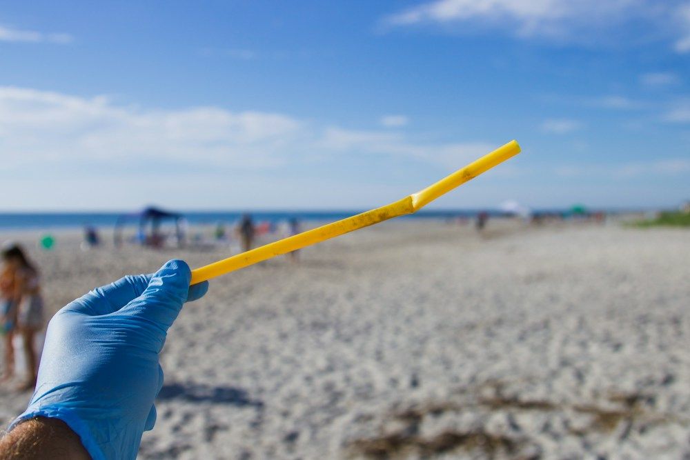 Hand holding a discarded plastic straw found at a beach
