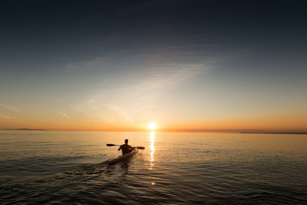 Kayaker paddling calm water at dusk