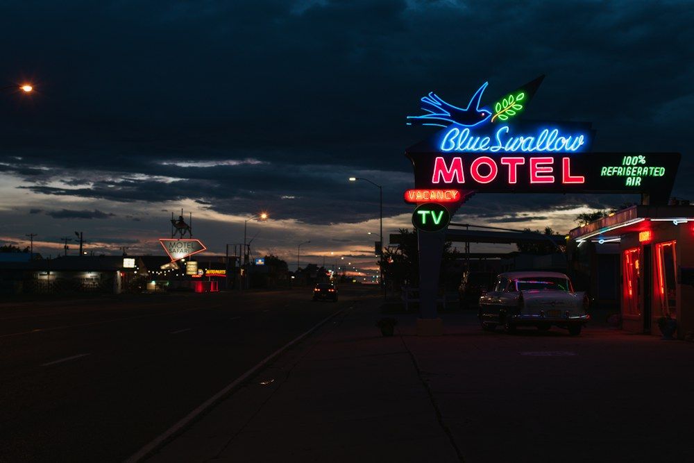 Neon Blue Swallow Motel sign glowing beside a highway at night