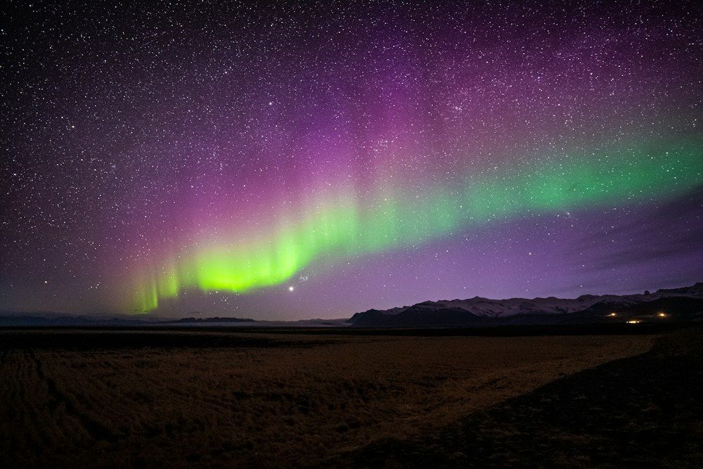 A bright purple and green aurora bore is in the sky