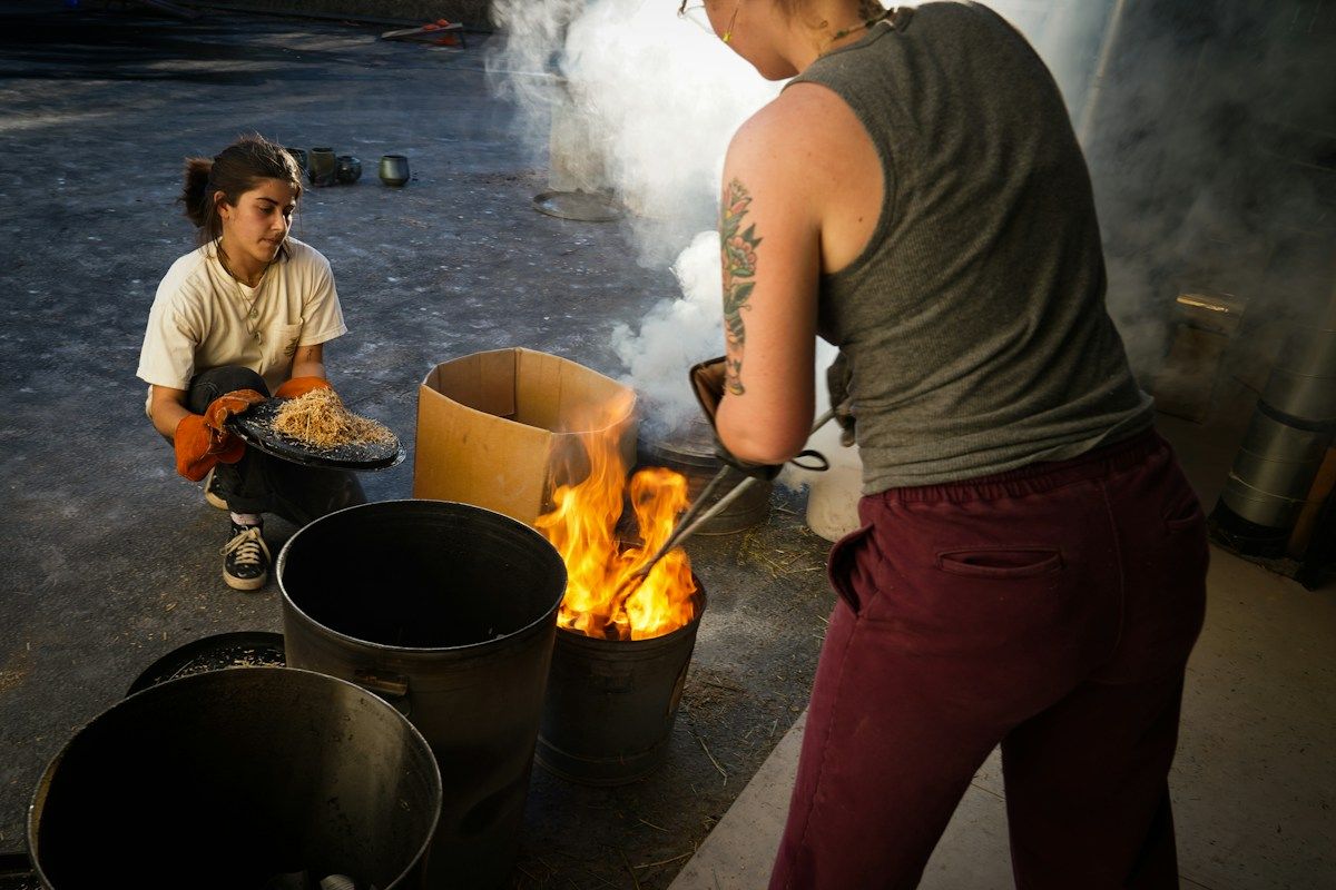 Potter working with fire and smoke during firing