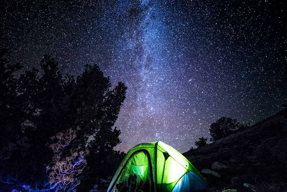 Lit tent beneath a star-filled wilderness sky