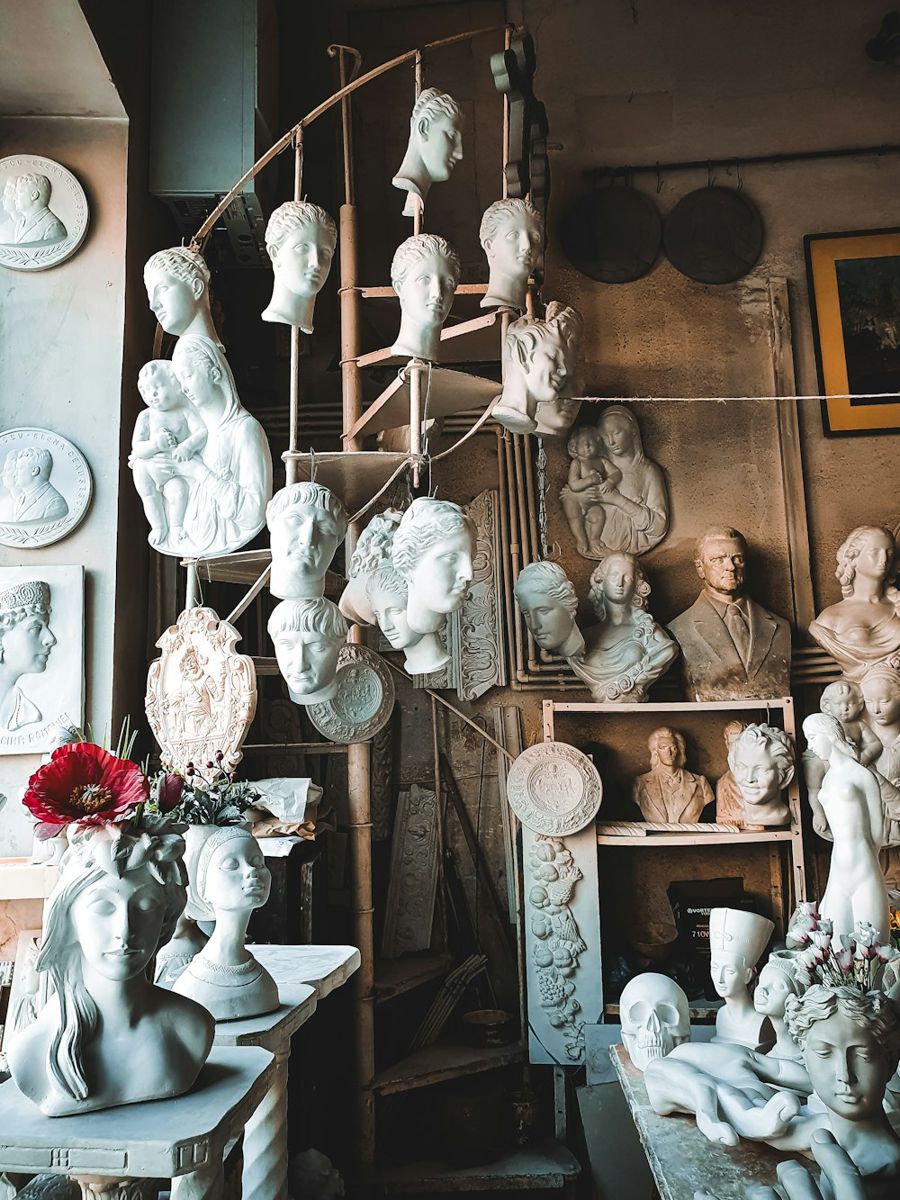 Artist's studio filled with white plaster sculptures and busts