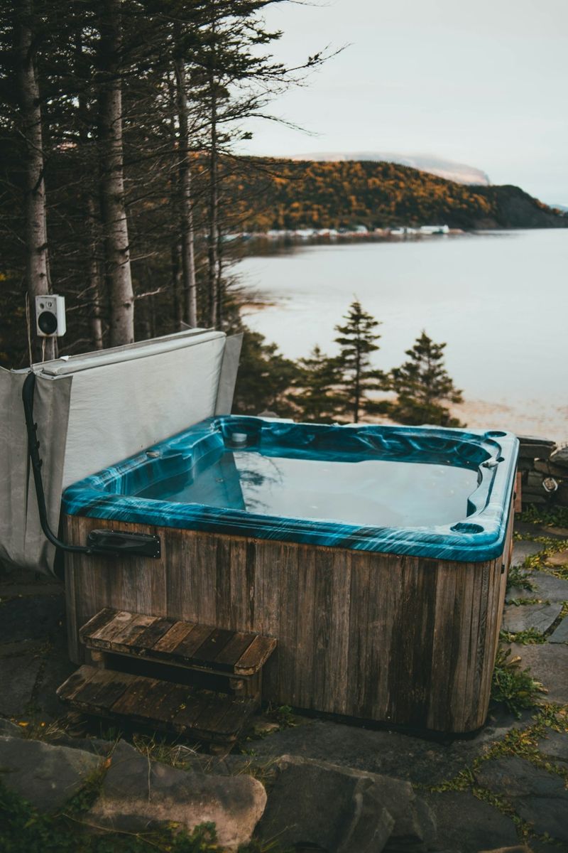 Outdoor hot tub on a wooden platform beside a lake