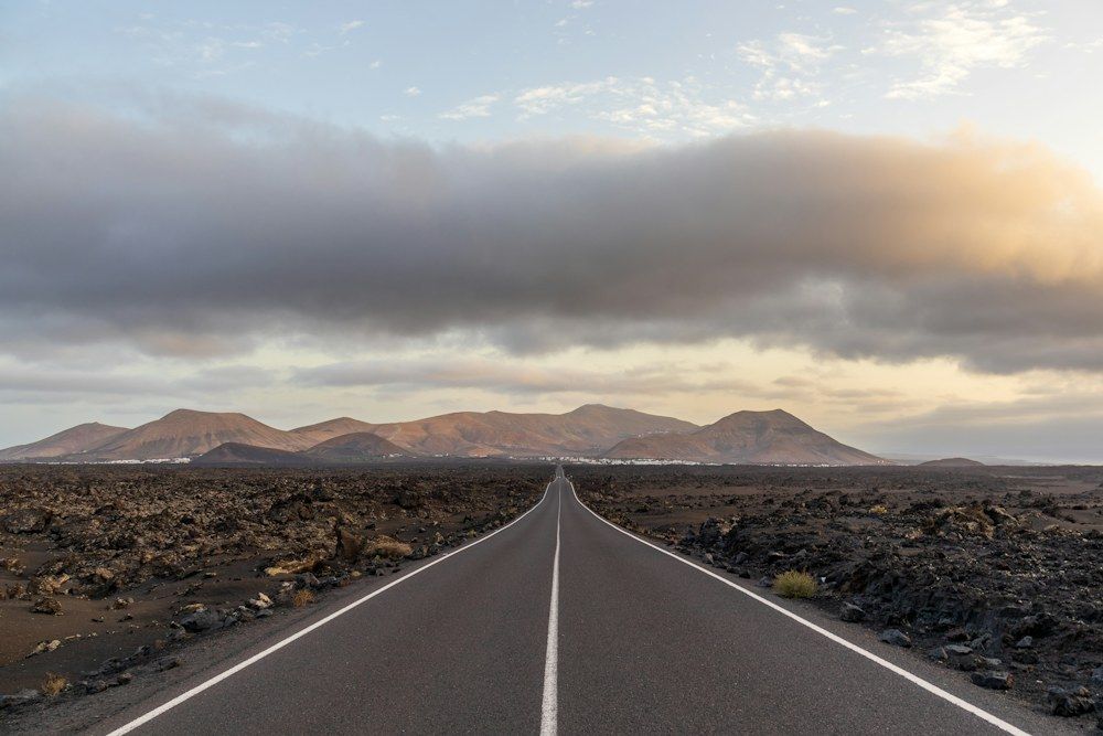 Straight road crossing Lanzarote's dark volcanic landscape