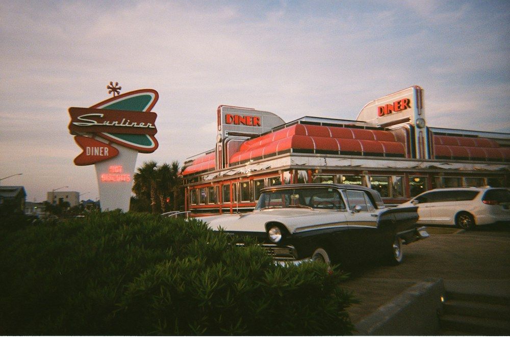 An old car parked in front of a diner