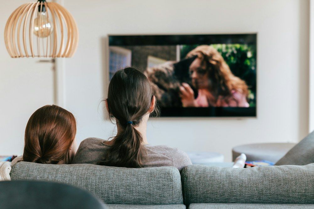 Two women on a couch watching television