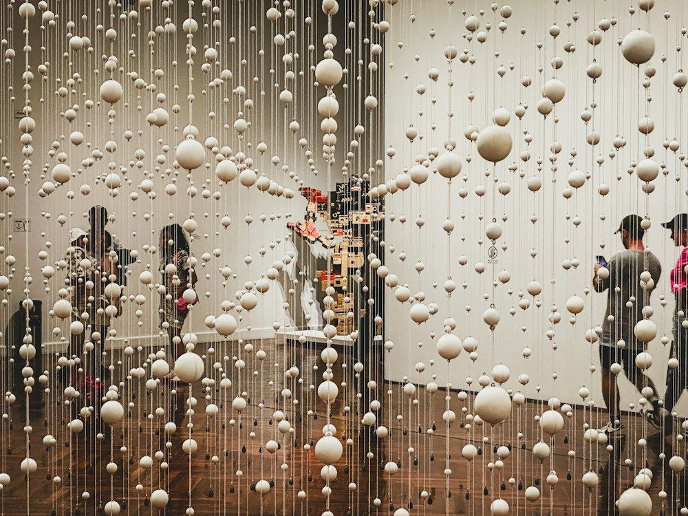 Visitors within a suspended bead art installation