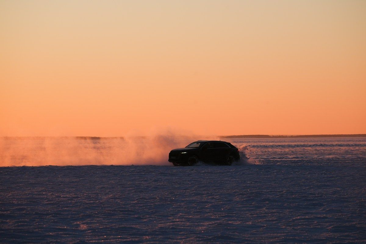 Car sliding across an icy plain at sunset