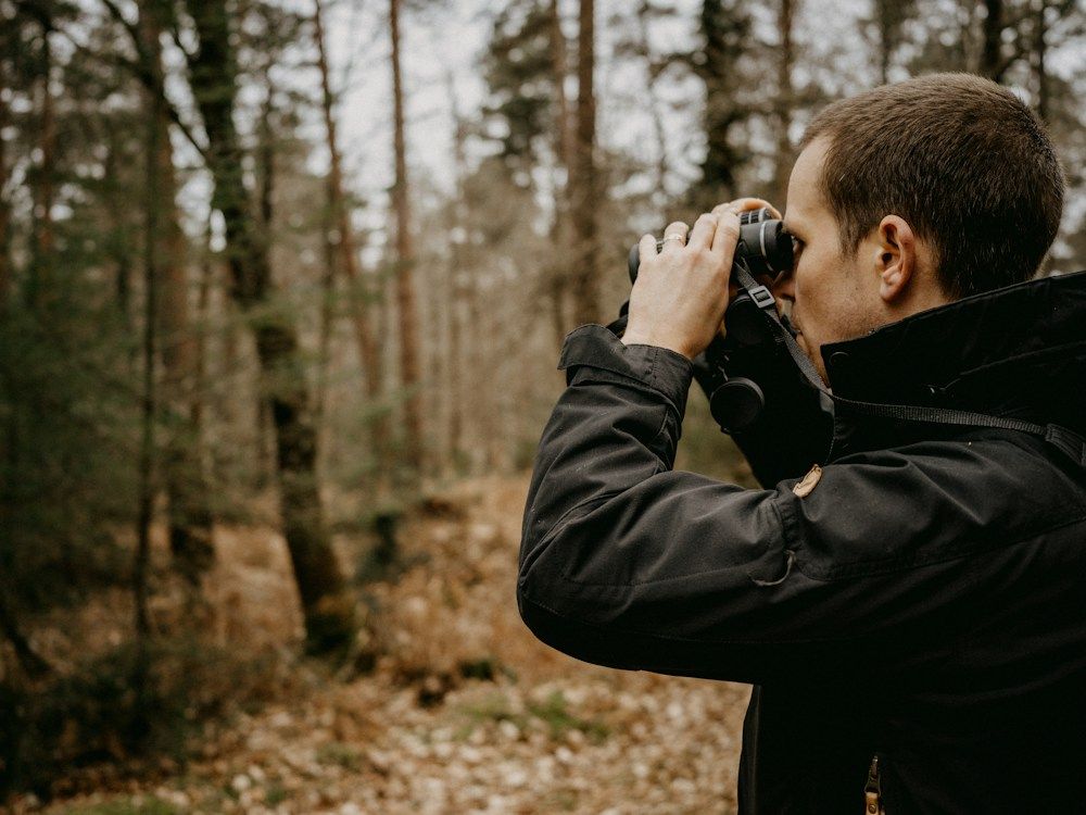 Birdwatcher using binoculars in a forest