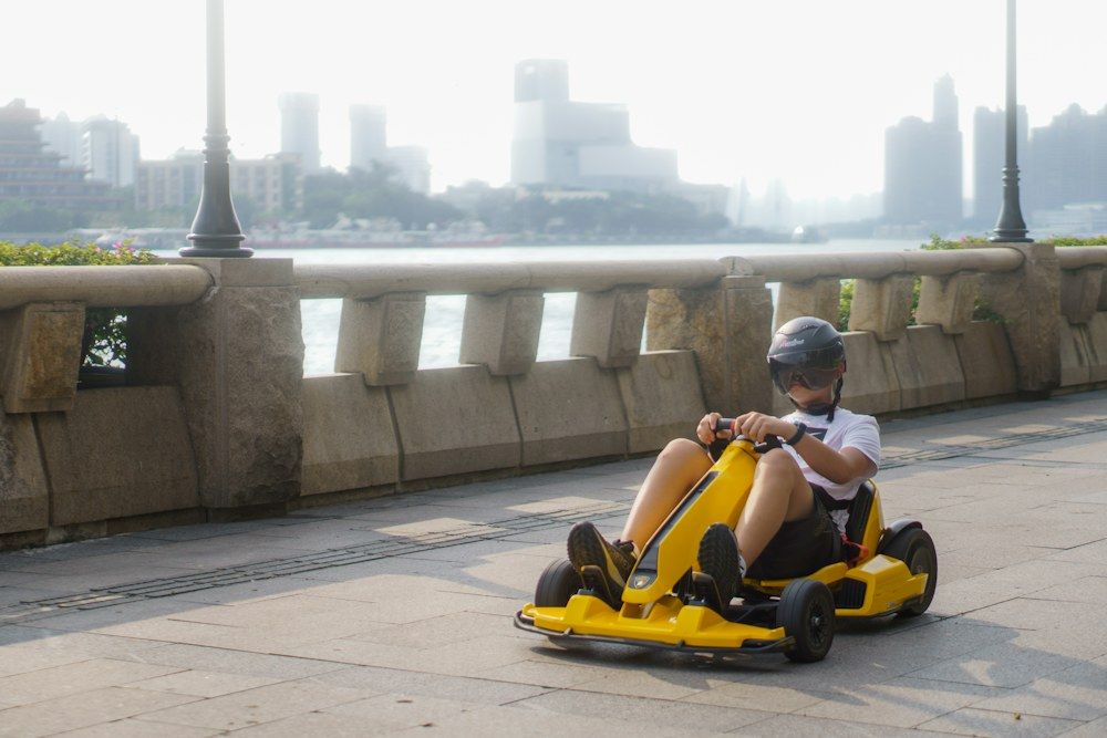 A young boy is riding a go - kart on a bridge