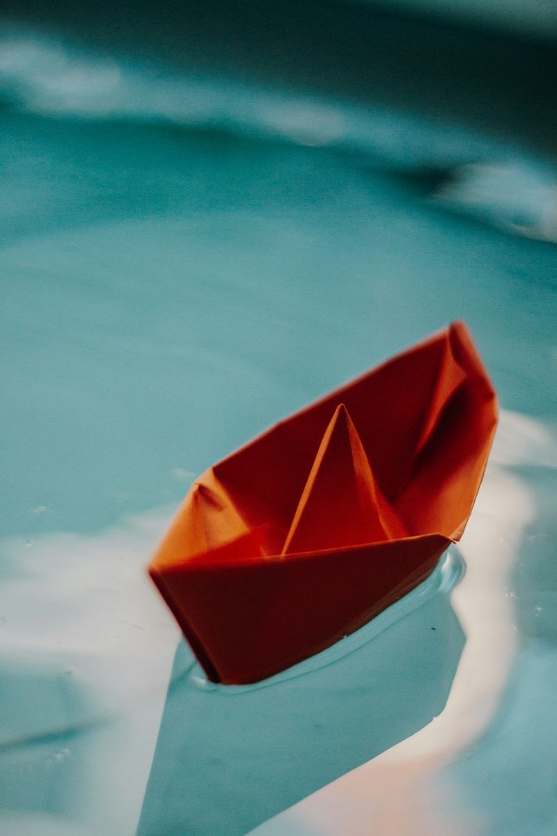 Orange paper boat floating on water