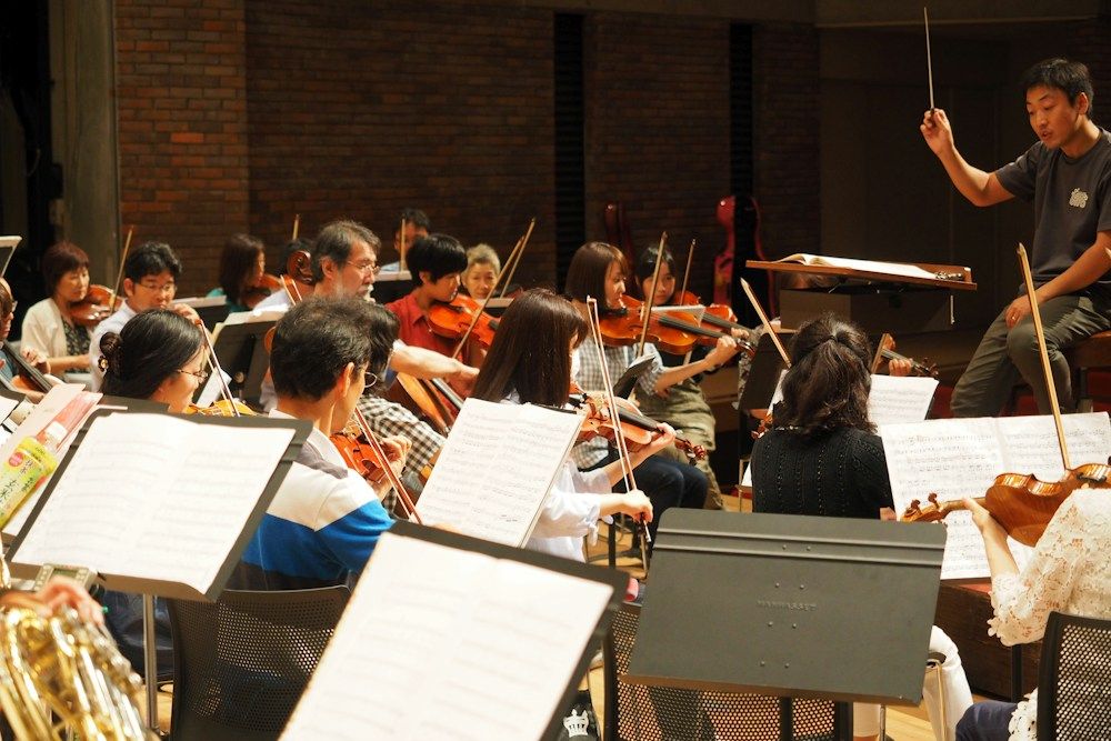 Orchestra musicians rehearsing with a conductor