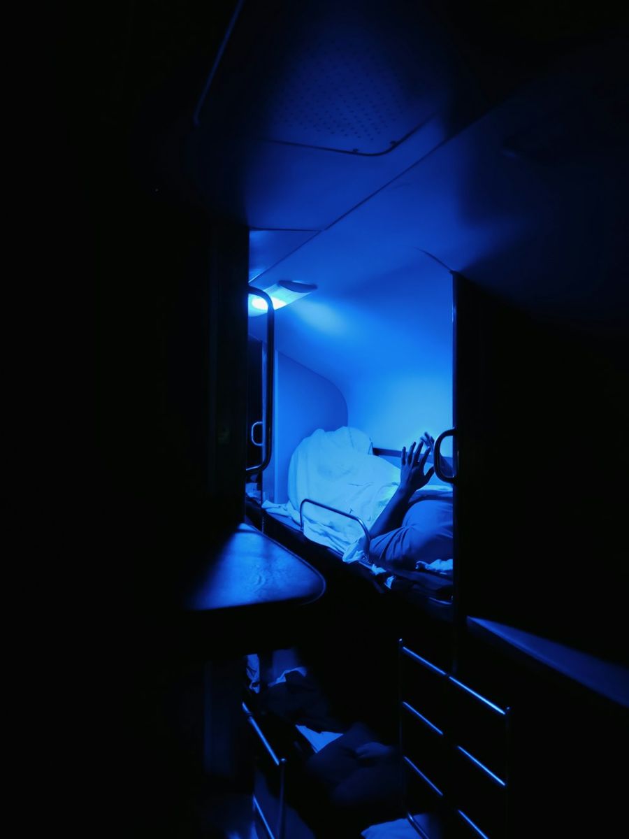 A dim train sleeper compartment with blue lighting.