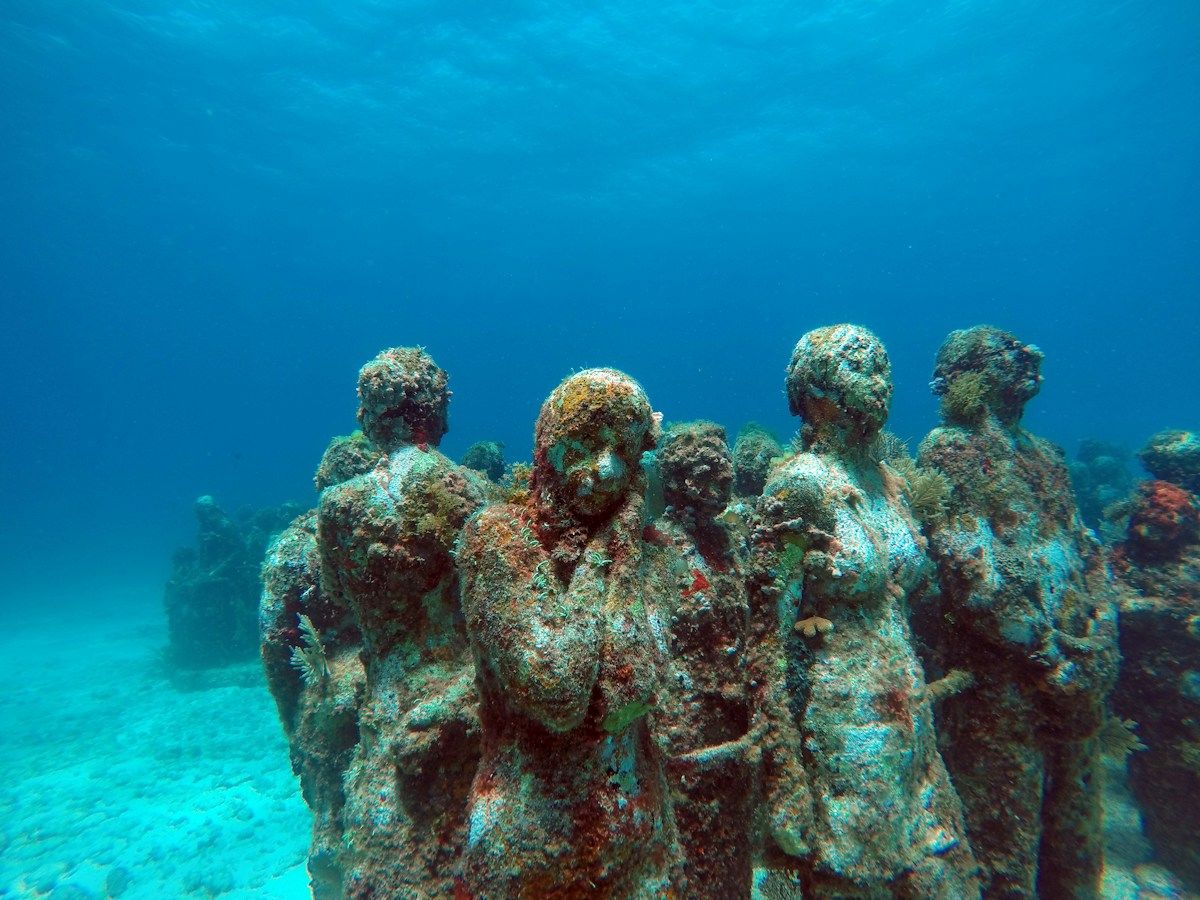 Underwater museum statues on a sandy seabed