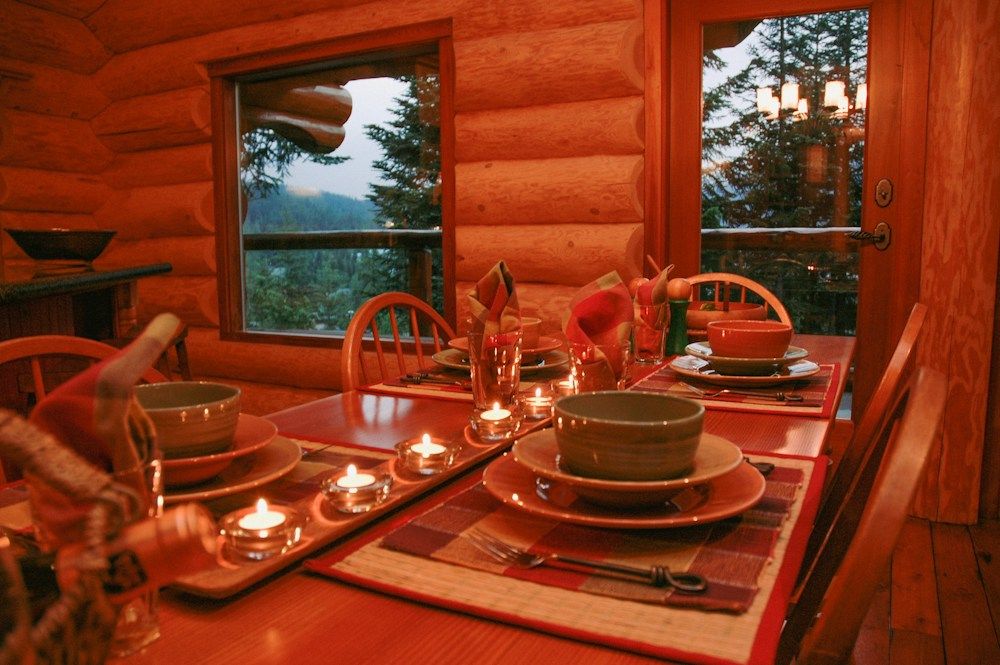 a dining room table set with place settings and candles