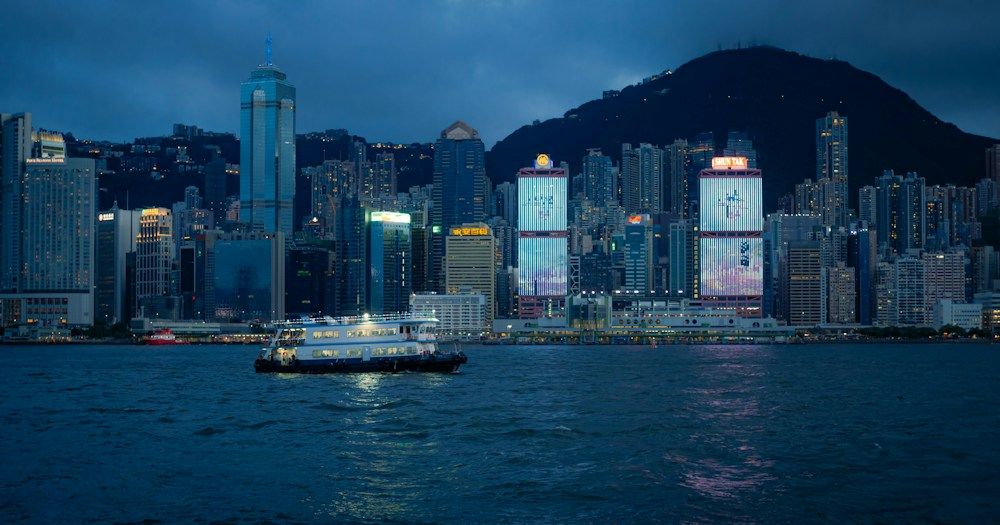Ferry crosses harbor with city skyline at dusk