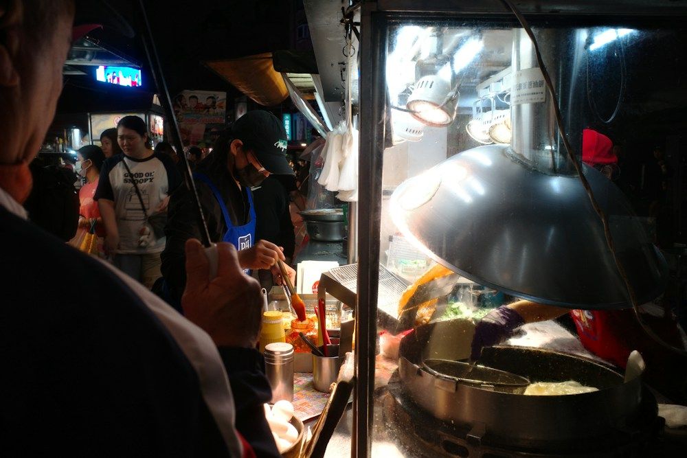 Vendor preparing food at a busy night market stall