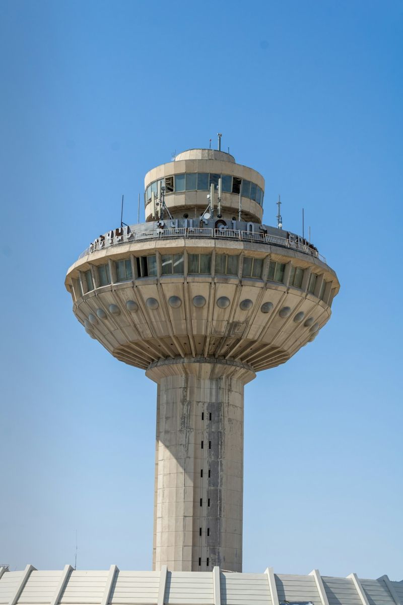 A concrete air traffic control tower rises against a clear blue sky at Zvartnots International Airport near Yerevan, Armenia.
