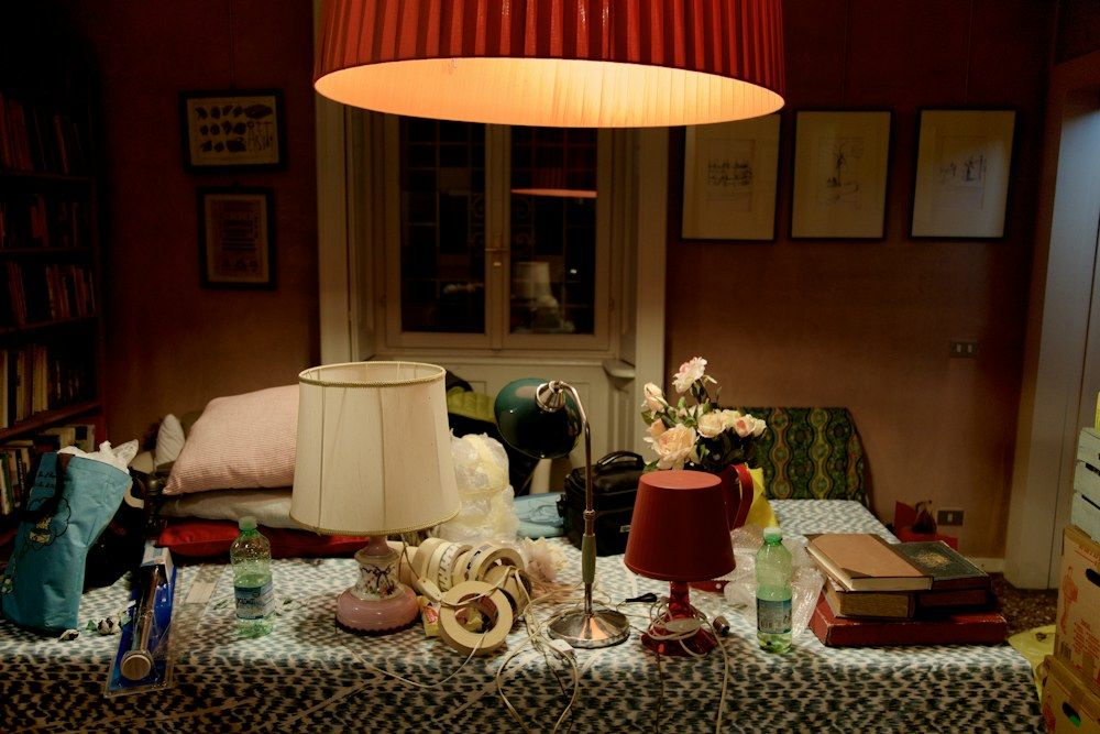 Lamp, books and flowers arranged as movie set props.