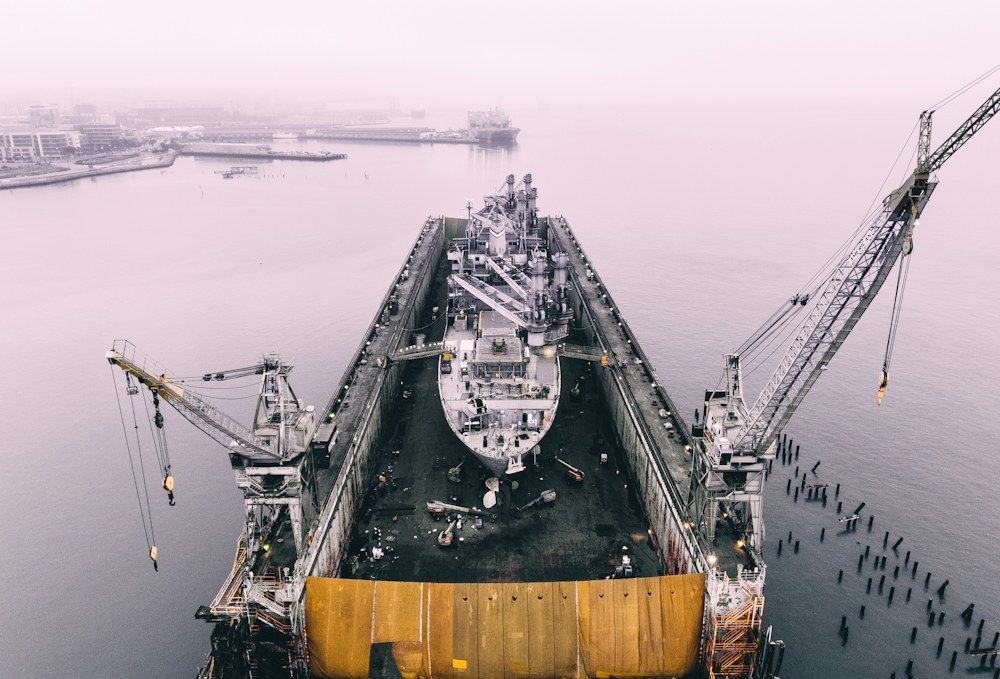 Large ship in a dry dock flanked by shipyard cranes