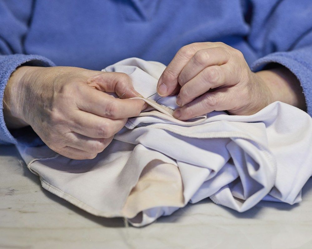 Hands sewing a patch onto fabric