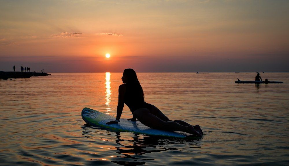 Woman practicing yoga on a paddleboard at sunset