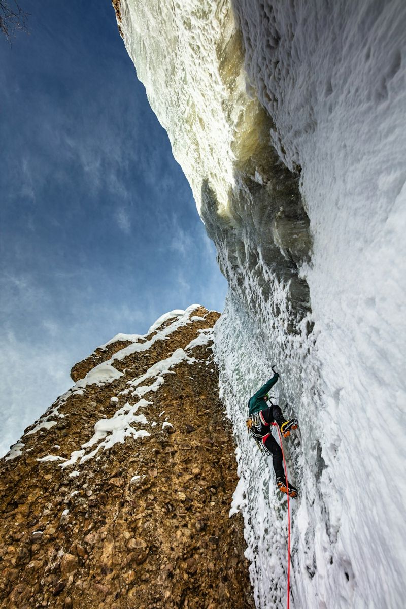 Ice climber on a vertical frozen wall with safety rope