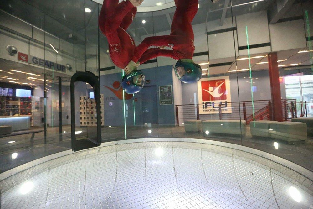 Two instructors flying inside an indoor wind tunnel