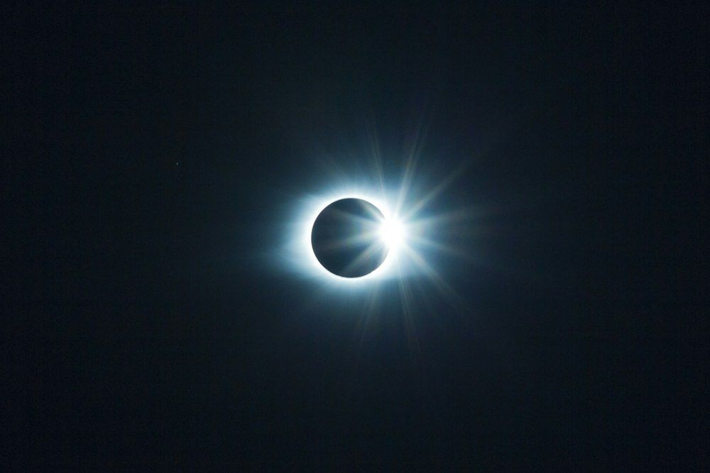 A breathtaking photograph by Tyler van der Hoeven captures the precise moment of a total solar eclipse, showcasing the diamond ring effect as the sun’s corona peeks around the moon’s dark silhouette.