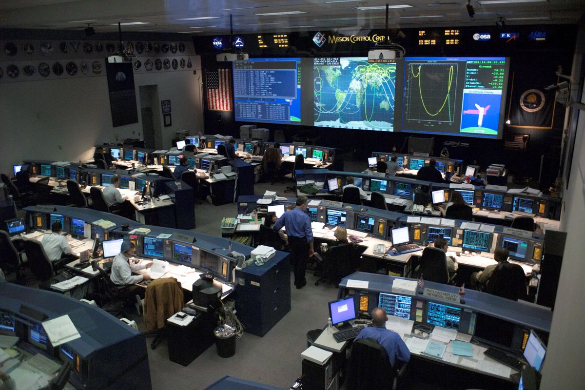 NASA flight controllers at consoles in the Johnson Space Center mission control room