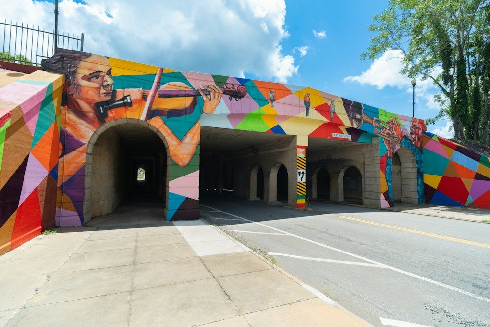 A vibrant street art installation covers the concrete arches of an overpass bridge in Macon, United States.
