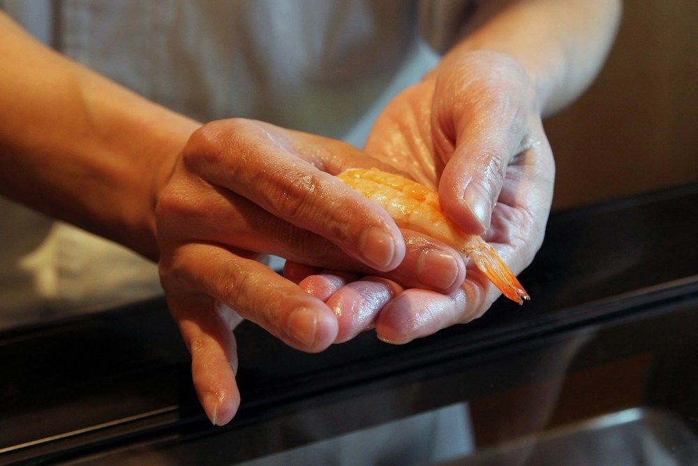 Chef shaping shrimp nigiri by hand